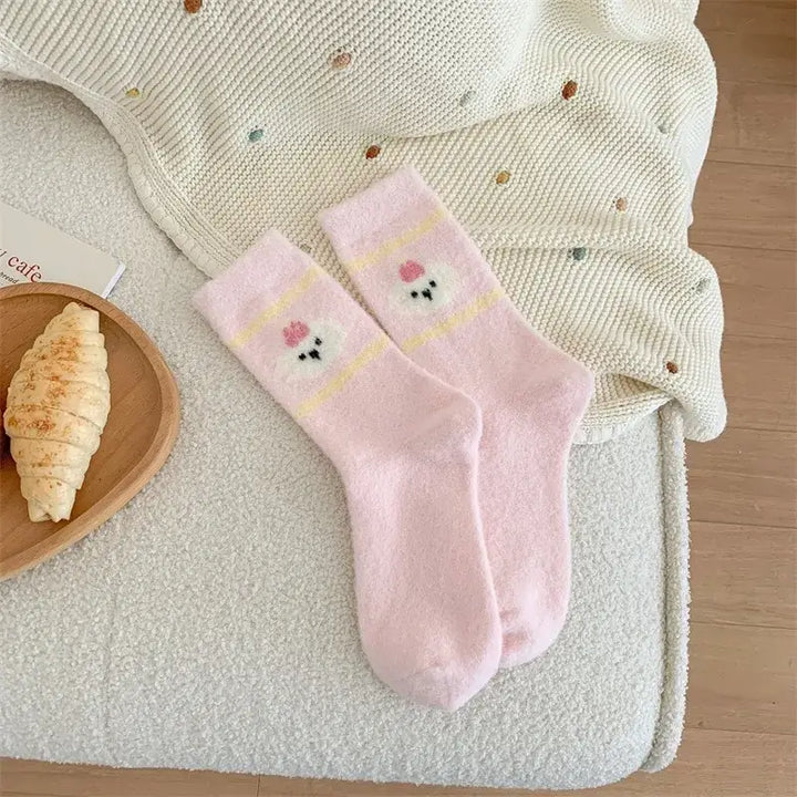 Kósýsokkar - hvítir og bleikir with cartoon head design, pink and white striped, cozy Australian velvet socks on a comfy home setting.